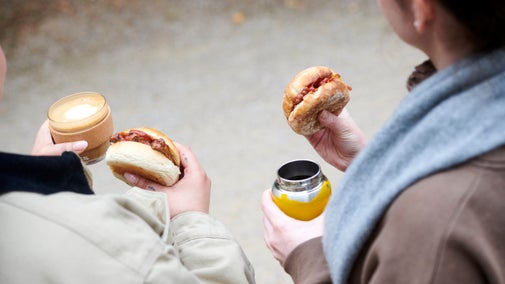 Visitors wearing coats and scarves enjoying coffee and a bap in winter